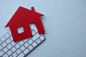 Red paper house icon placed beside computer keyboard