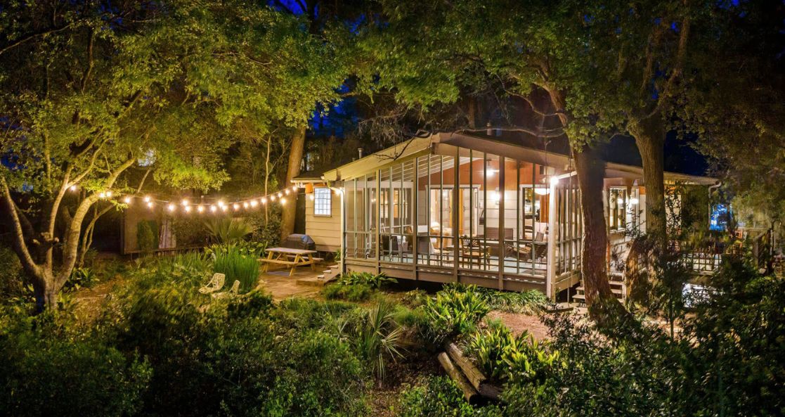 Folly Beach short-term rental home surrounded by trees and outdoor lights at night